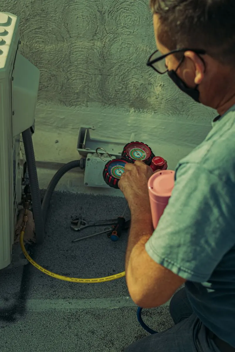 HVAC technician checking an outdoor unit with tools in hand